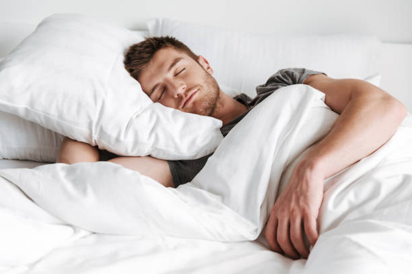 Handsome young man sleeping in bed stock photo